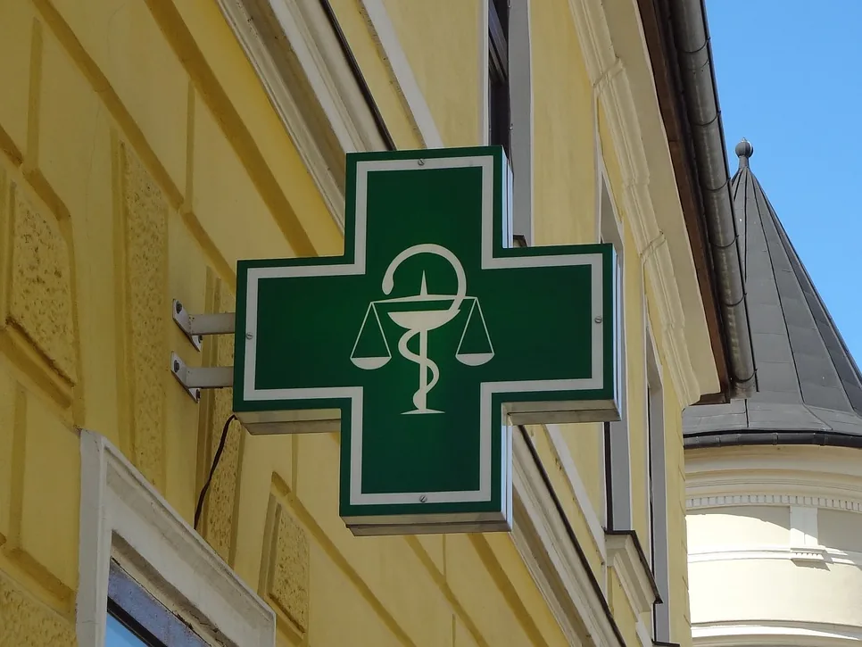 Croix de pharmacie allumée dans une rue, la nuit